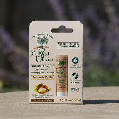 Foto del bálsamo labial Le Petit Olivier en su empaque, apoyado sobre piedra con fondo natural desenfocado