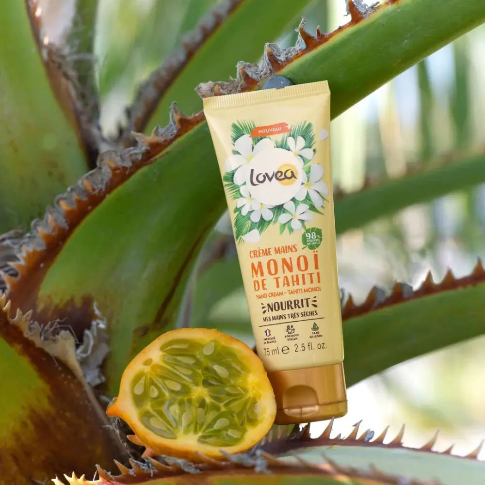 Crema de manos Lovea Monoi de Tahití apoyada sobre una planta de aloe vera con maracuyá abierto, resaltando ingredientes naturales