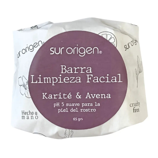 Jabón en barra de limpieza facial Sur Origen de karité y avena, pH 5 suave para la piel del rostro, envase ecológico blanco con etiqueta circular morada, hecho a mano y cruelty free.