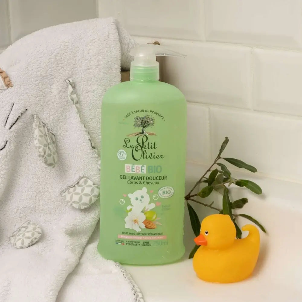 Foto de gel lavant Le Petit Olivier Bébé Bio en tina de baño junto a toalla infantil y patito de goma